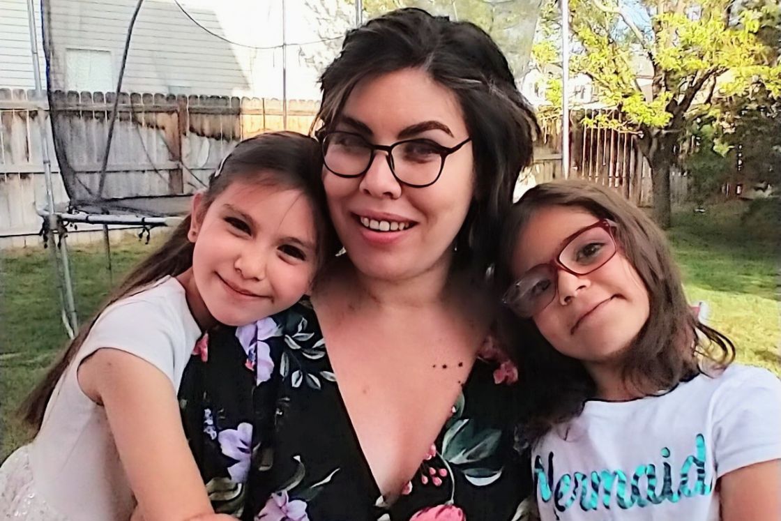 Deb and two girls smile in backyard area