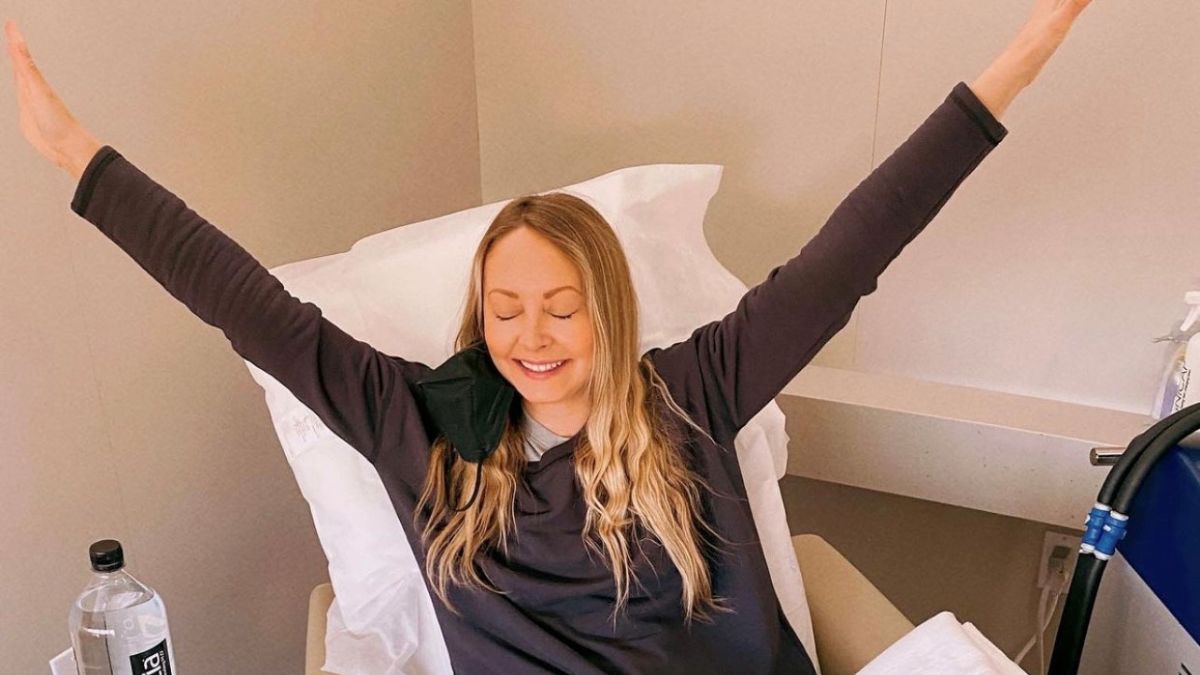 Young woman with blond hair raises arms in victory