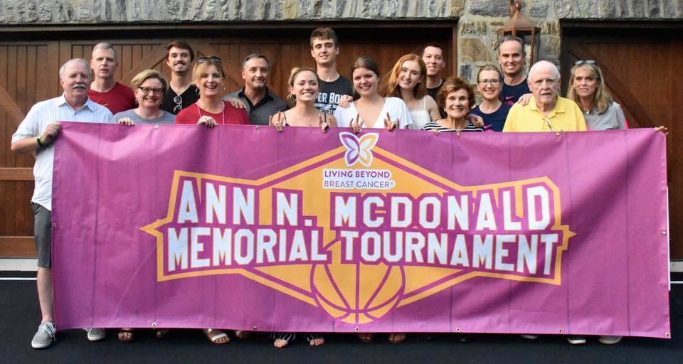 A group of people holding a large banner that says, "Ann N. McDonald Memorial Tournament"