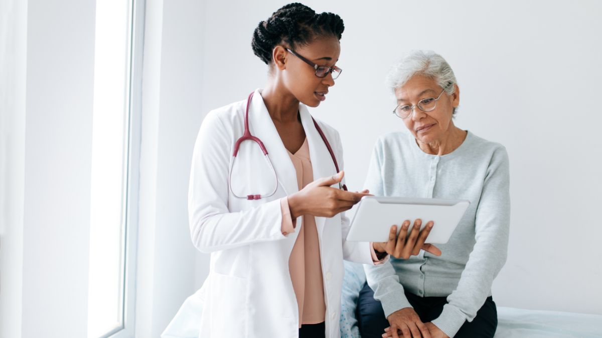 A Black female physician reviews medical info with an elderly patient