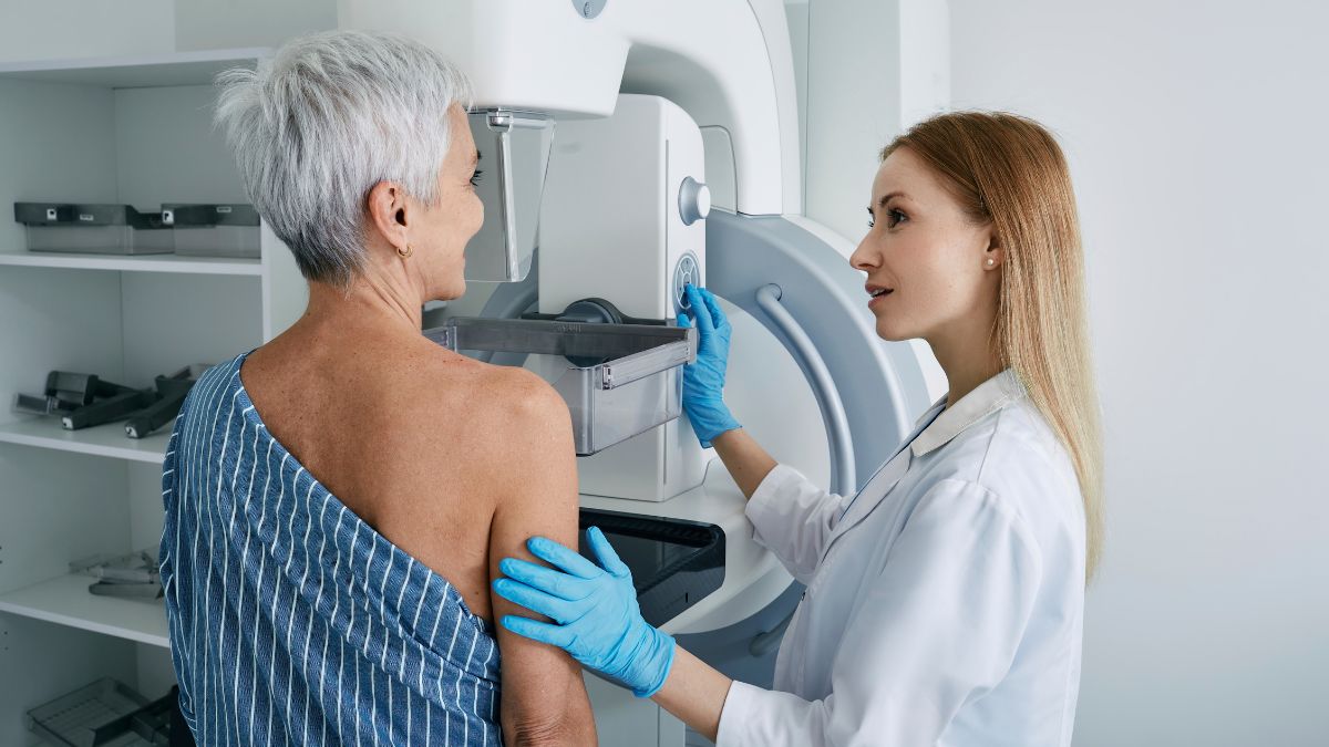 A healthcare provider assists an older woman with her mammogram