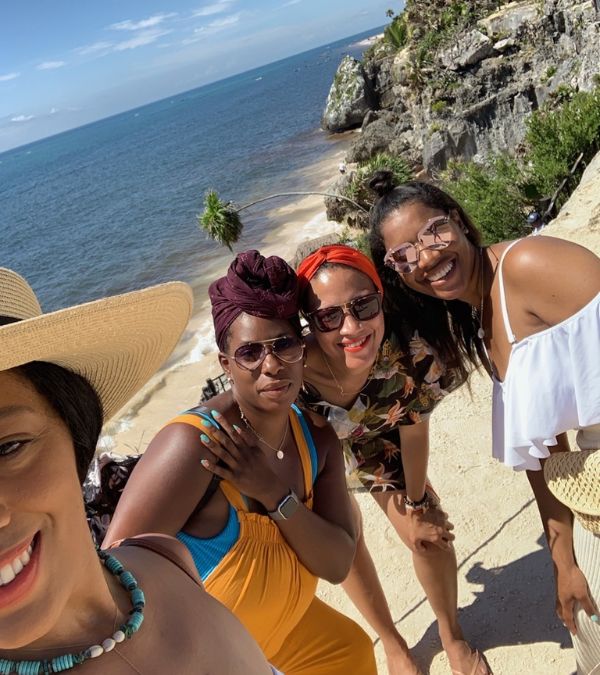Young Black women link arms at the beach in Tulum