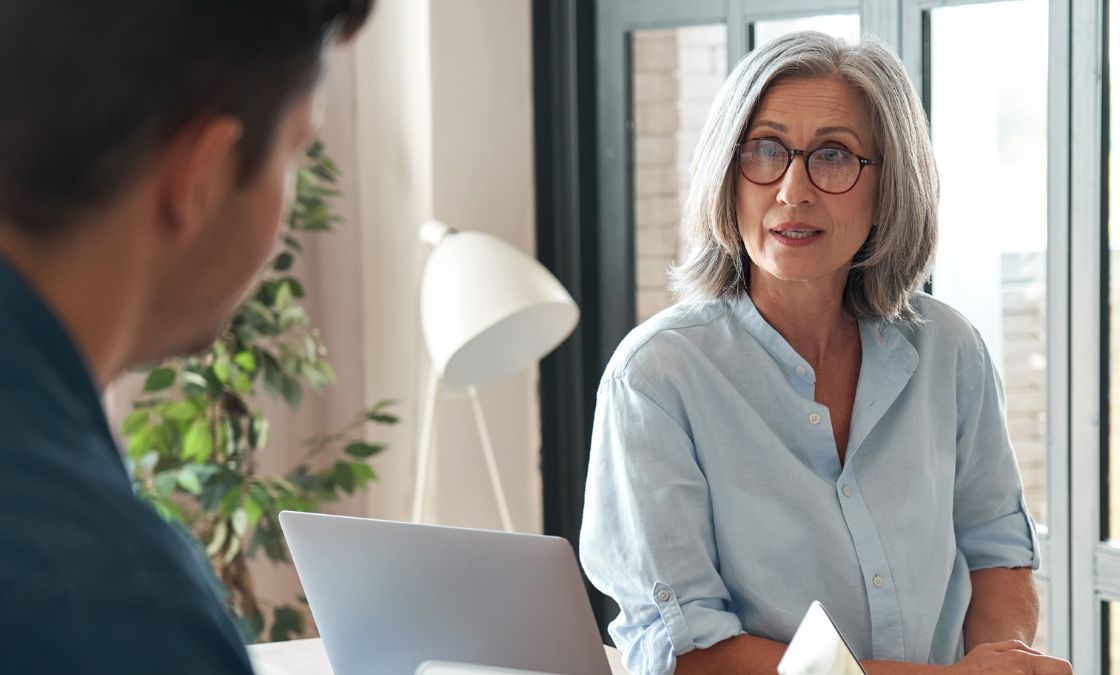A woman sits across a desk from her supervisor