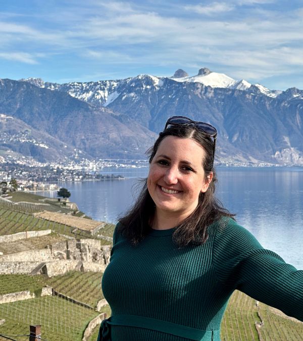 Lisa Francis stands in front of a beautiful Swiss mountain and lake vista