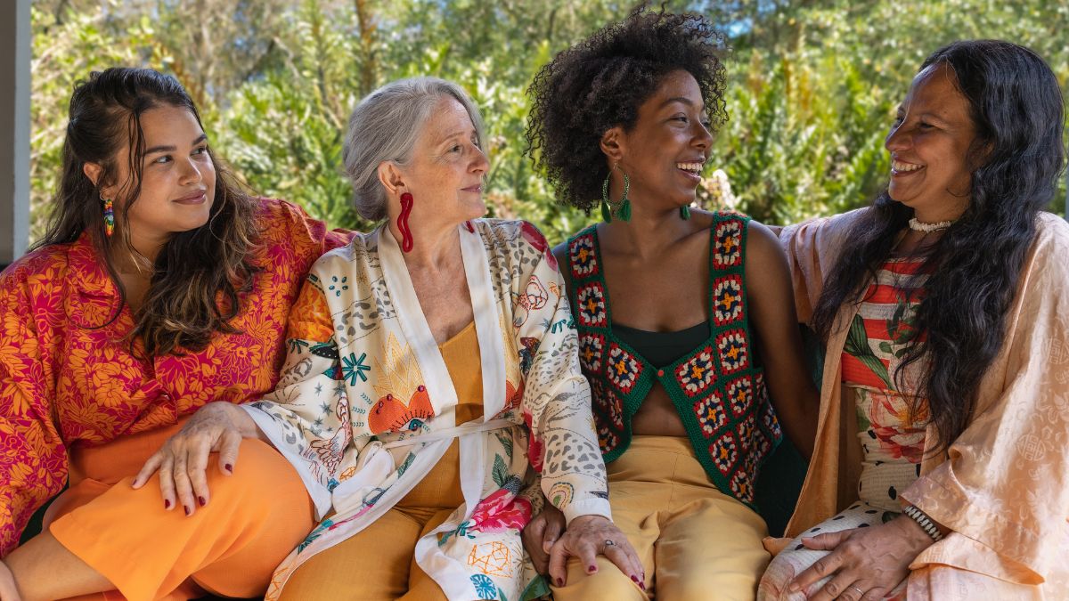 A group of women of diverse races and ages chat casually outside