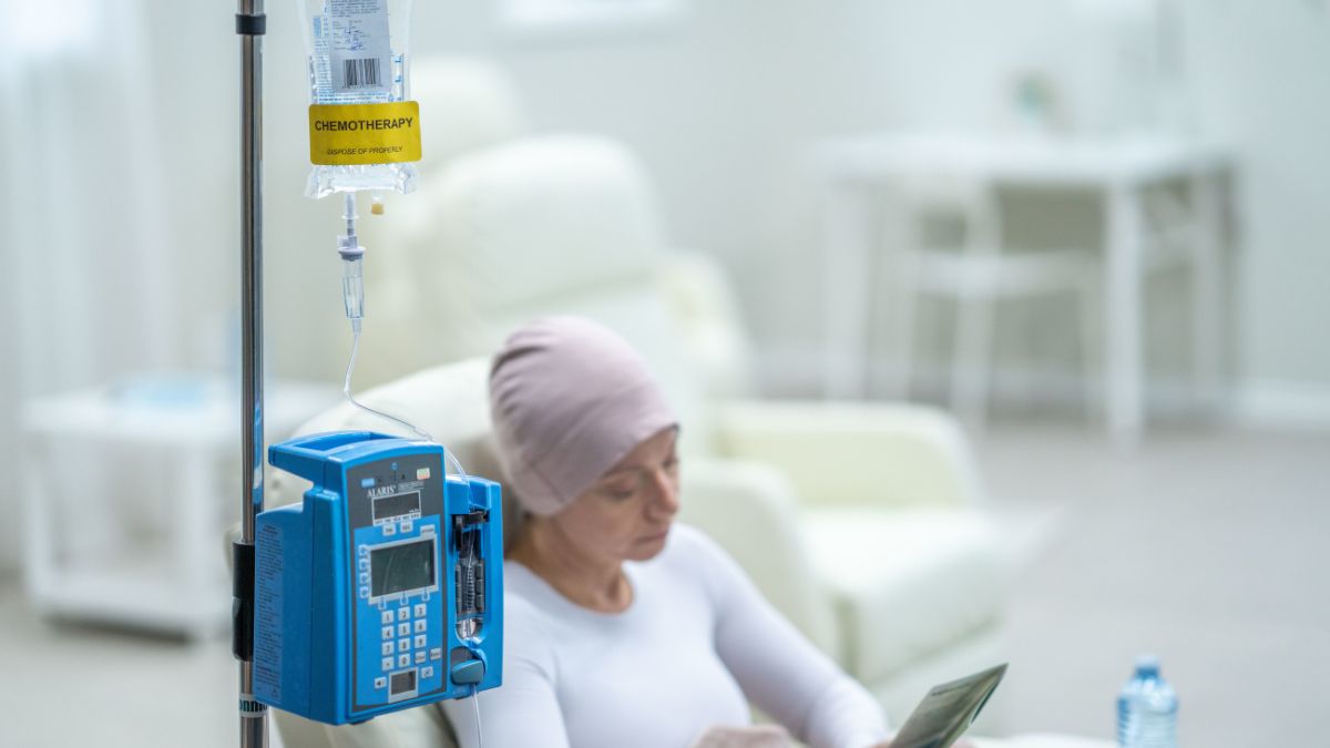 A woman reads beside a chemotherapy drip station