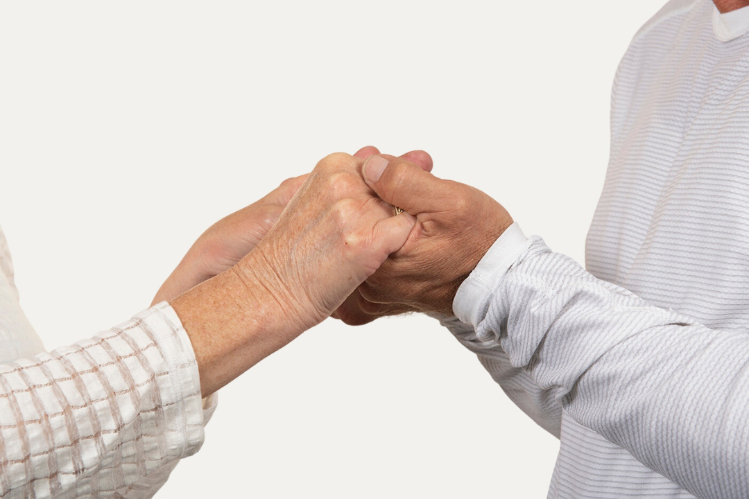 Close-up of two people facing each other, holding hands