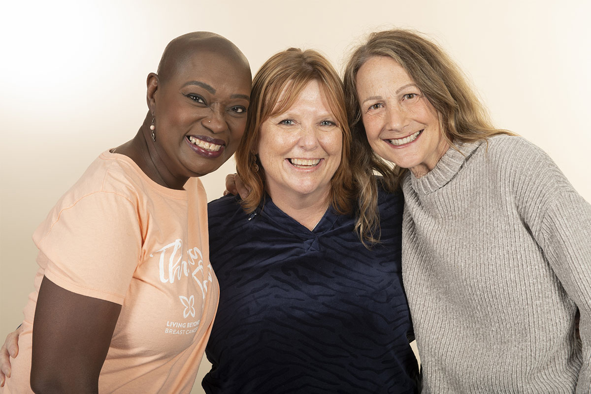 Group of three women, one Black, two white, smiling