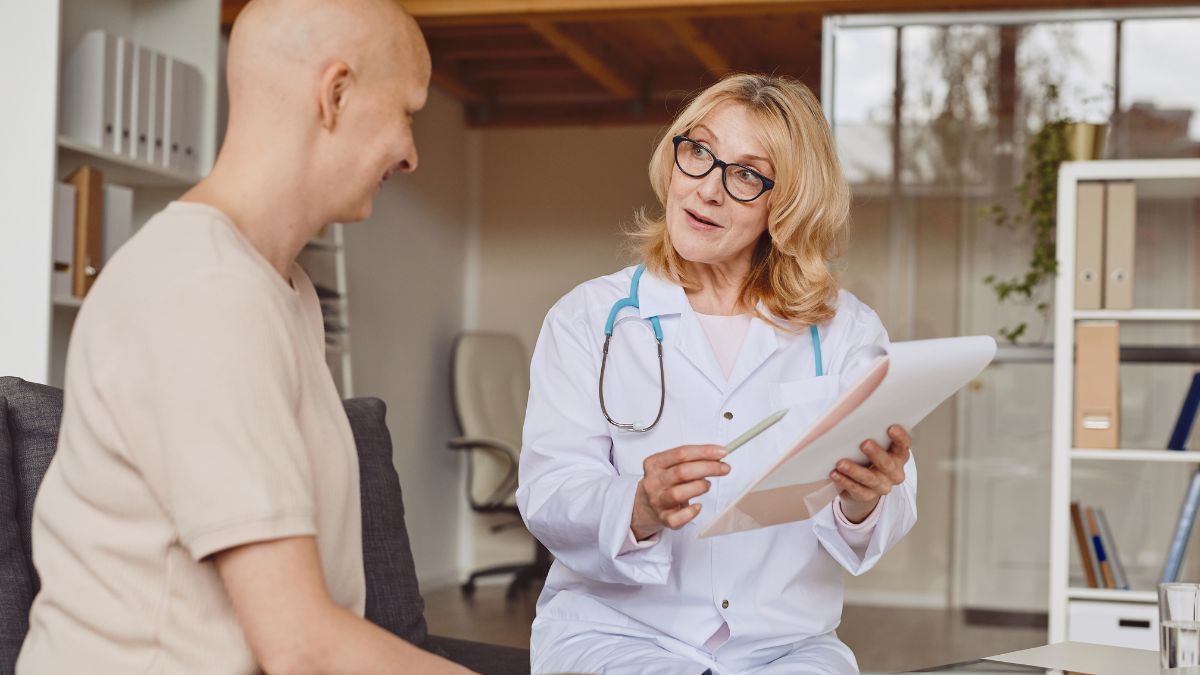 A breast cancer patient talks with her doctor who takes notes.