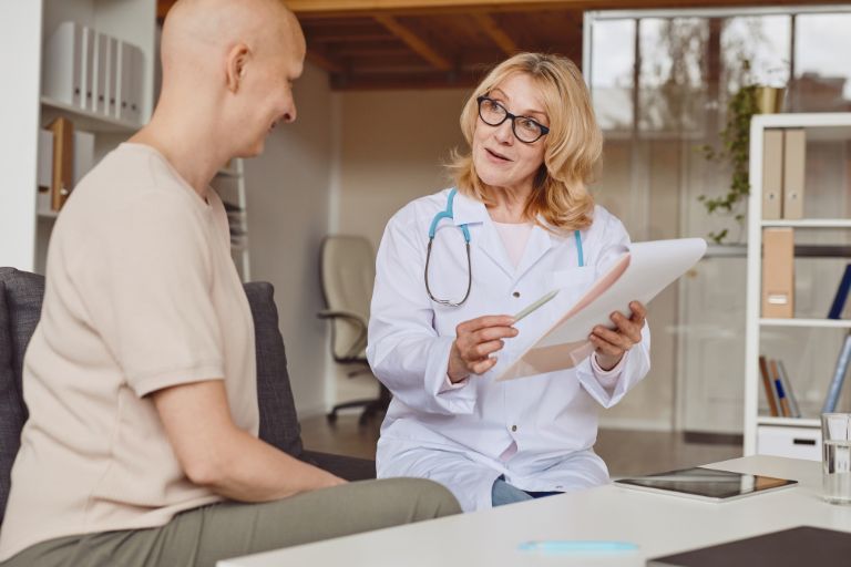 A breast cancer patient talks with her female doctor who takes notes.