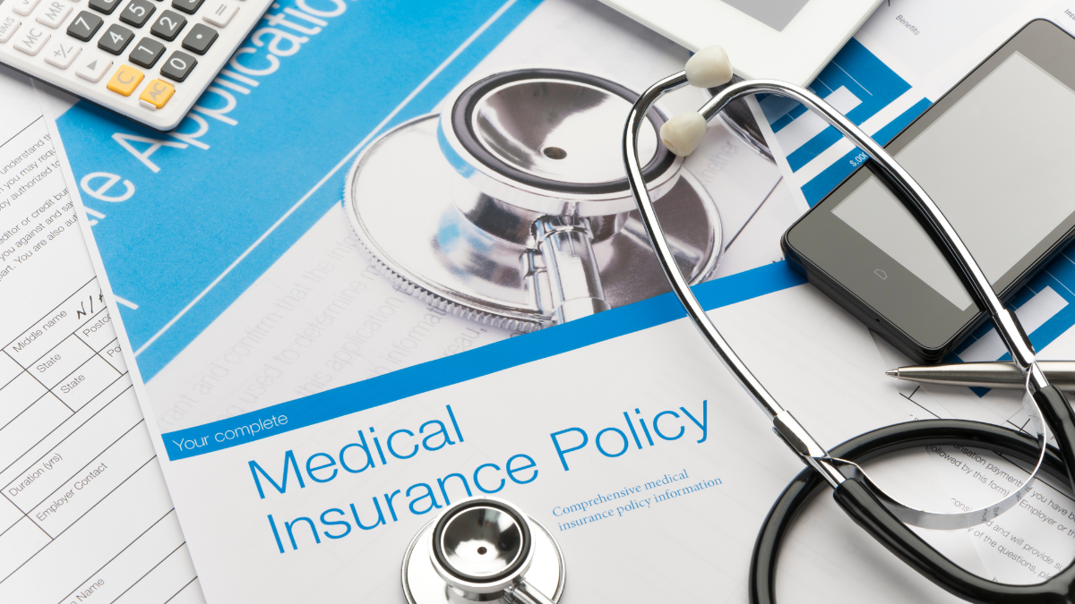 A calculator, stethoscope, and paper that says, "medical insurance policy."