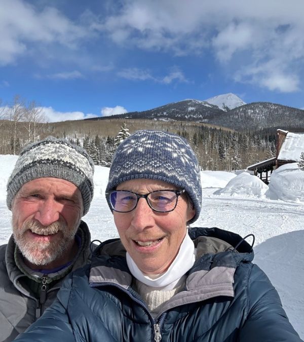 Mary Evelyn Burman and her husband take a selfie in a snowy mountain landscape.