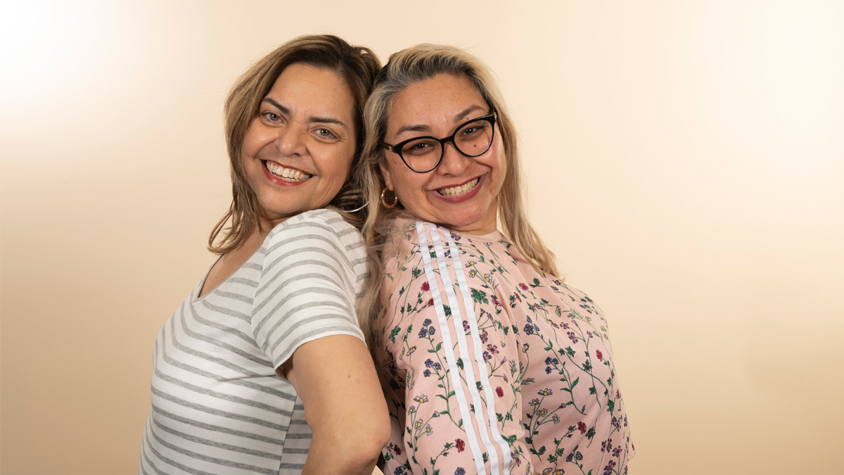 Two women of color smiling with their backs to each other.