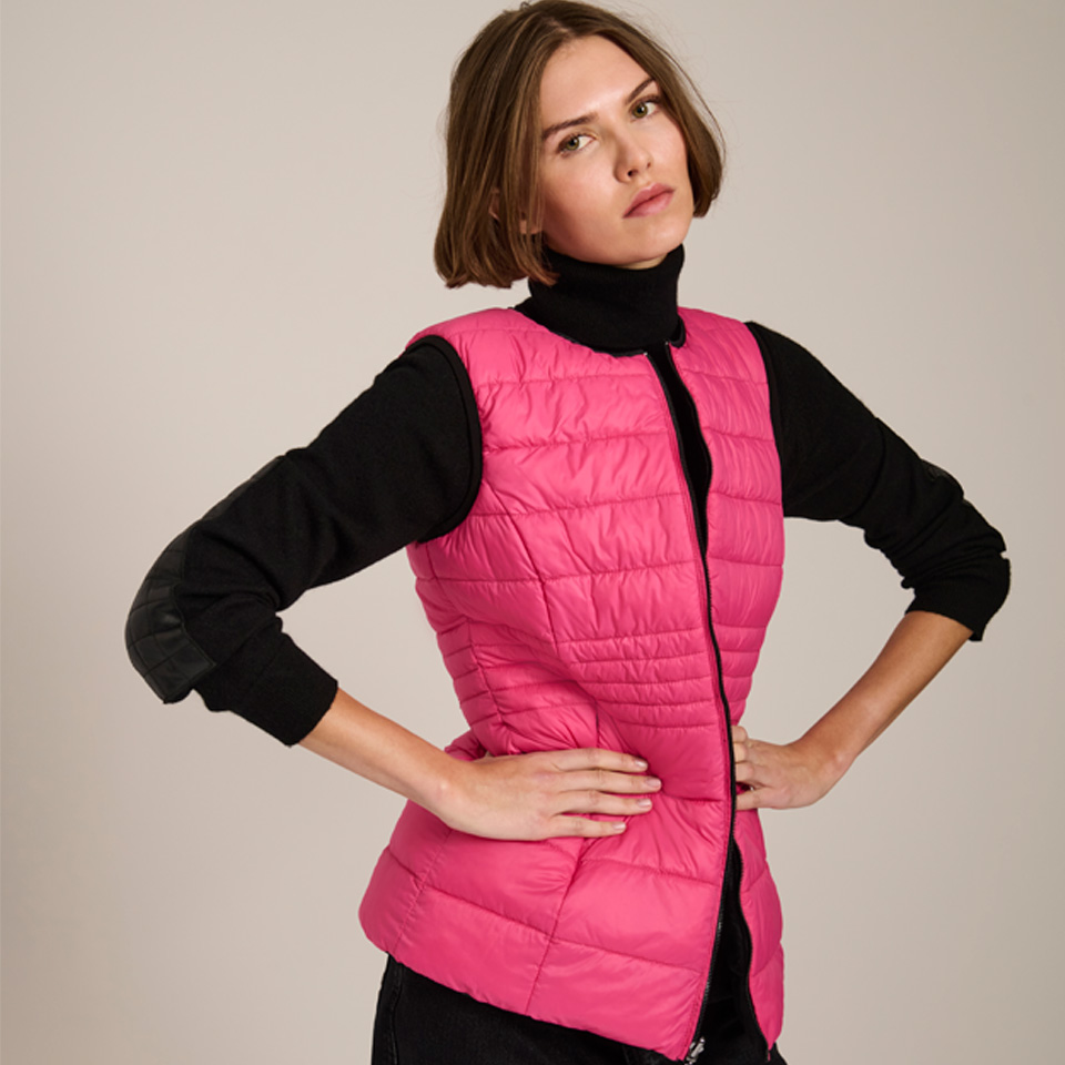 A white woman posing in a pink vest