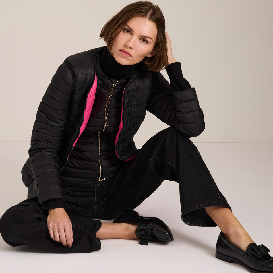 A white woman posing in a black vest