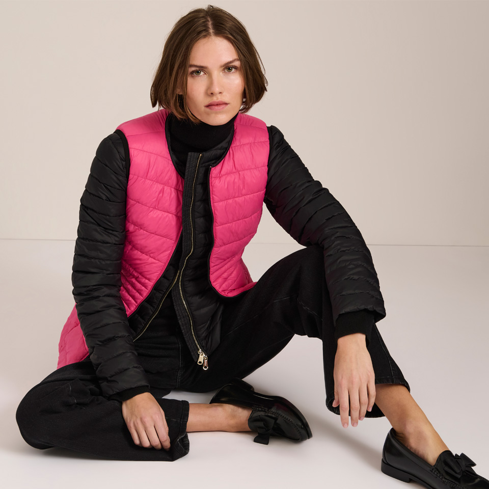 A white woman posing in a pink vest