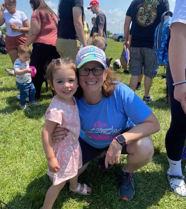 Aliza Feldman crouches down by a young girl at an outdoor event