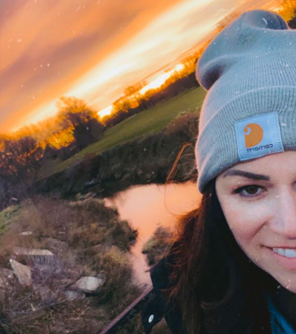 A white woman takes a selfie with a beautiful outdoor sunset