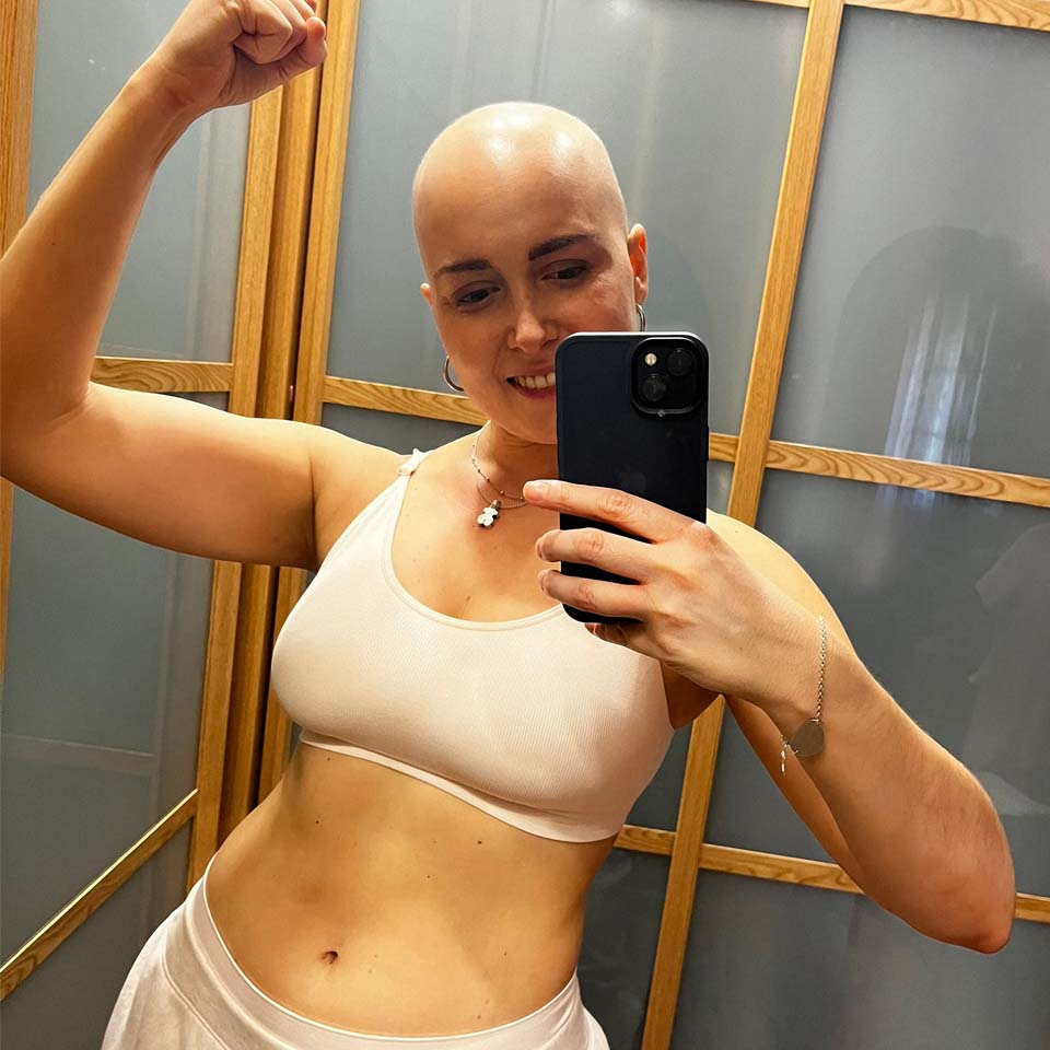 A woman flexing her biceps in a bra.