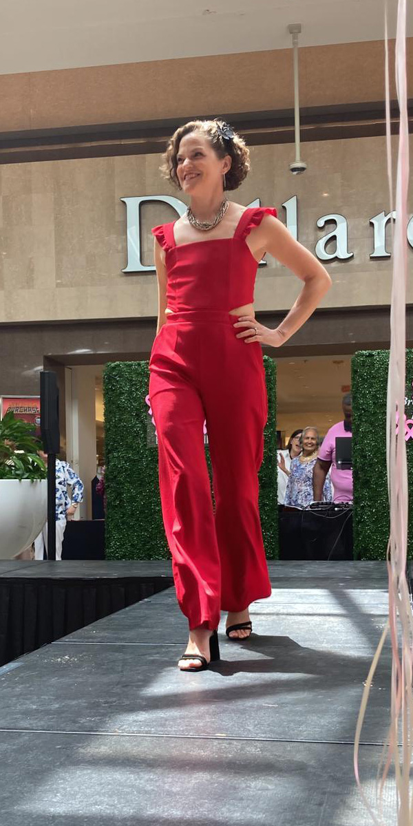 Rosemary walks the runway in a bright red pantsuit