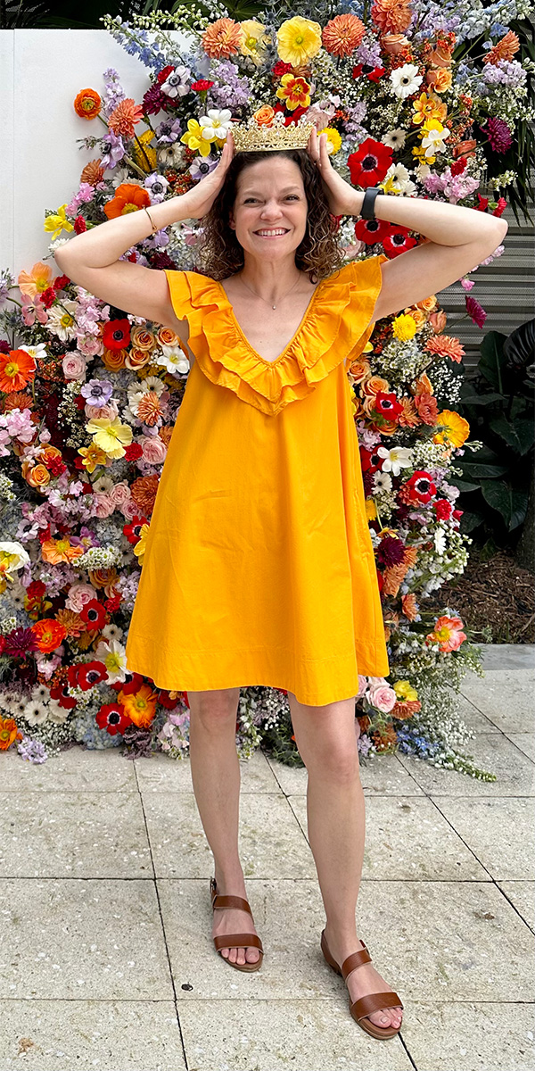 Rosemary places a crown on her head while wearing a bright yellow dress