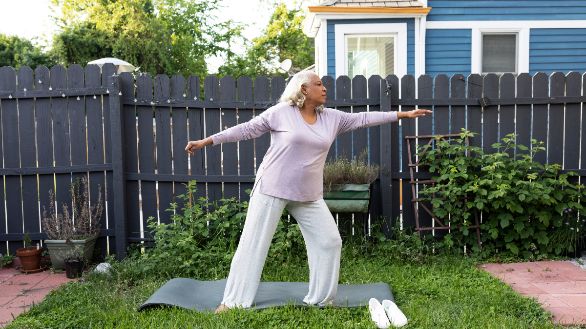 Older Black woman does yoga in her backyard