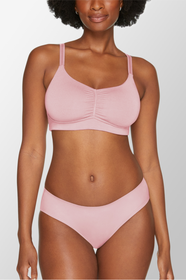 A Black woman wearing a pink bra and underwear set