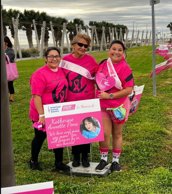 Ashlynn Gomez and two women old a sign in memory of Ashlynn's mom