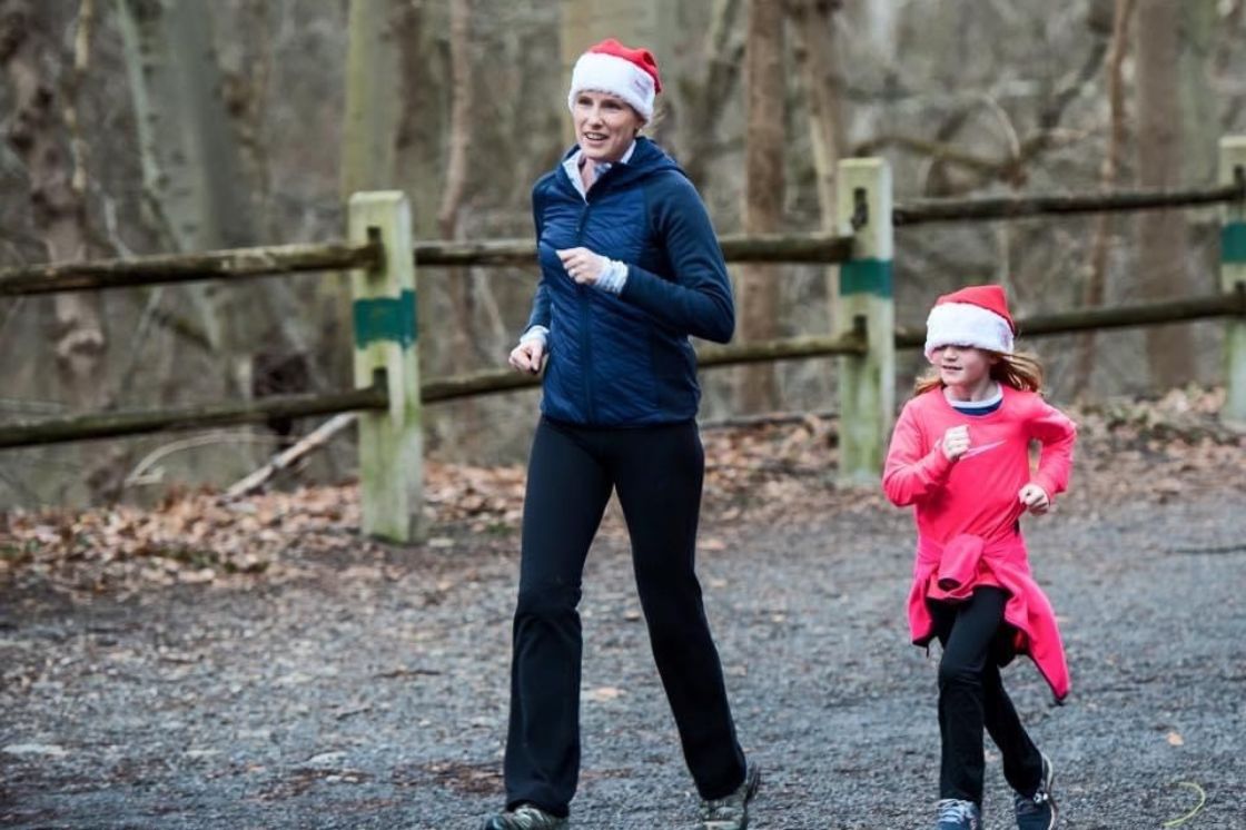 Megan runs with her young daughter on a nature hike, wearing Santa hats