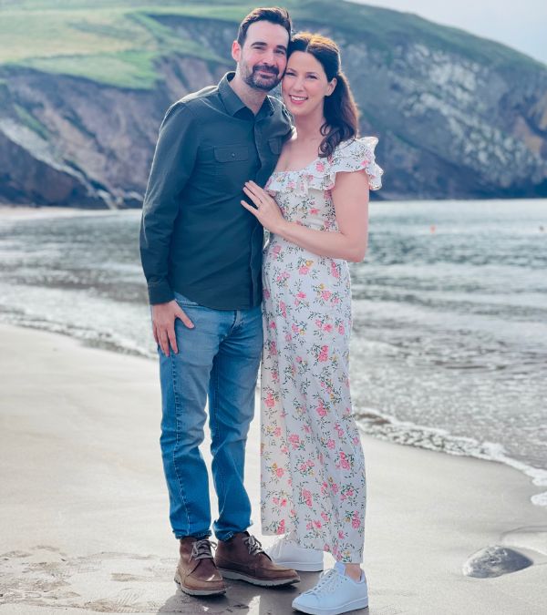 Megan O'Neill and her husband at the beach, a cliff behind them