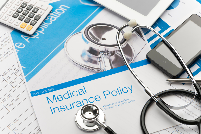 A calculator, stethoscope, and paper that says, "medical insurance policy."
