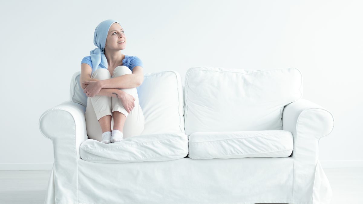 White woman on sofa, hugging her knees happily