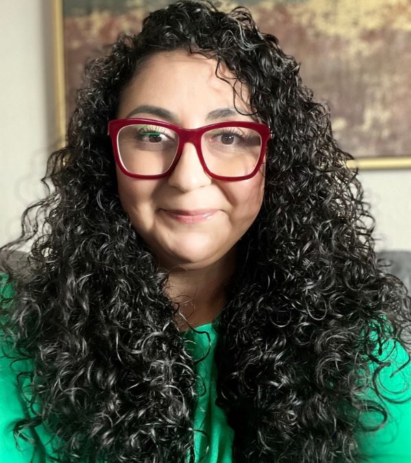 Headshot of Adriana Huerta in red glasses and green top