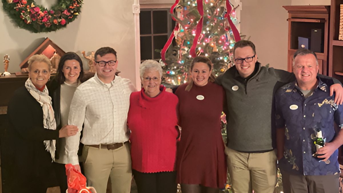 Jacqueline Beck and her large family stand before a Christmas tree