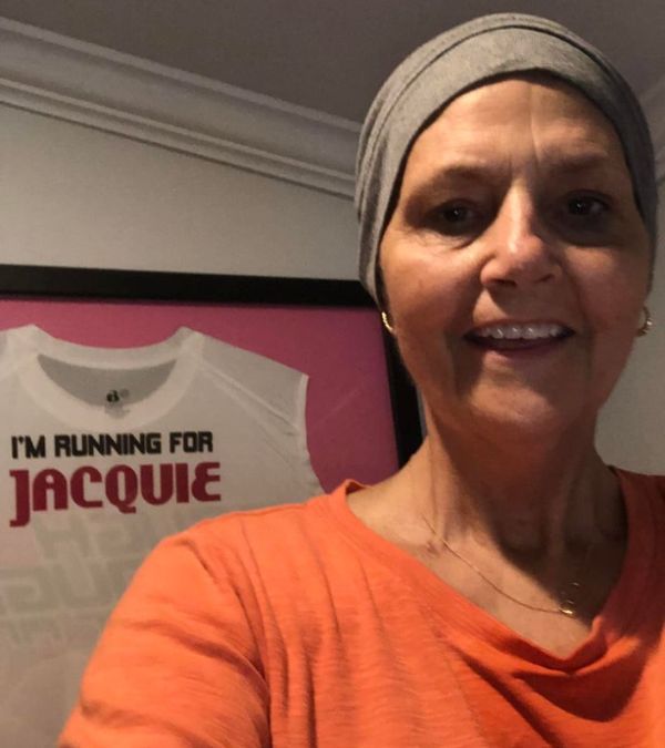 Jacqueline Beck wears a workout beanie and poses in front of a framed t-shirt in her honor
