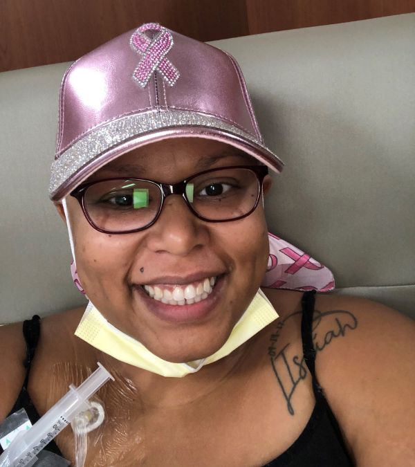 Stephanie Smith wears a metallic pink baseball cap as she receives chemo