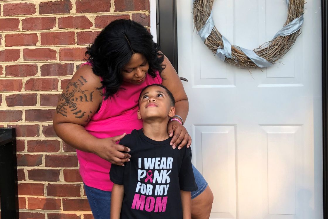 Stephanie Smith and her son share a tender look in front of their home's entrance