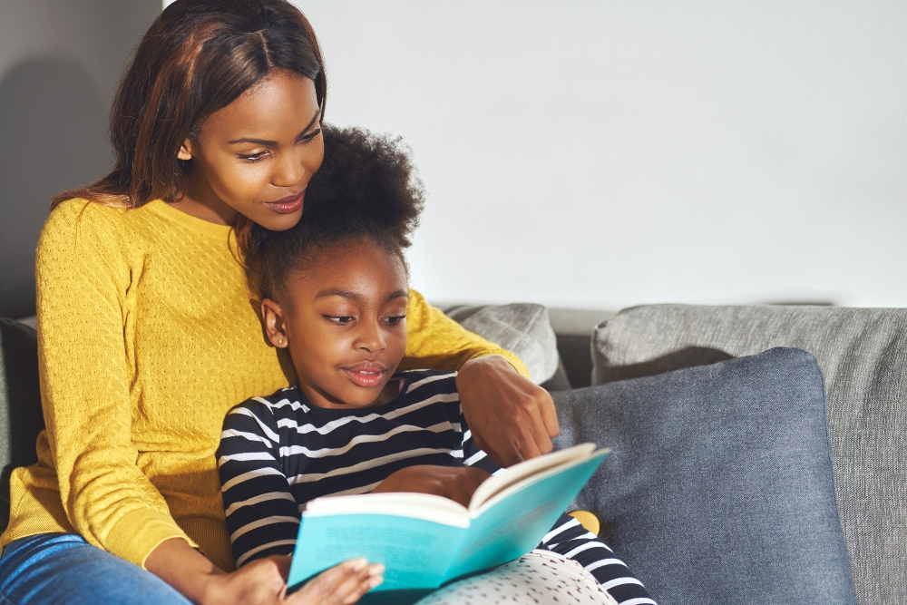 Black mother and daughter reading a book