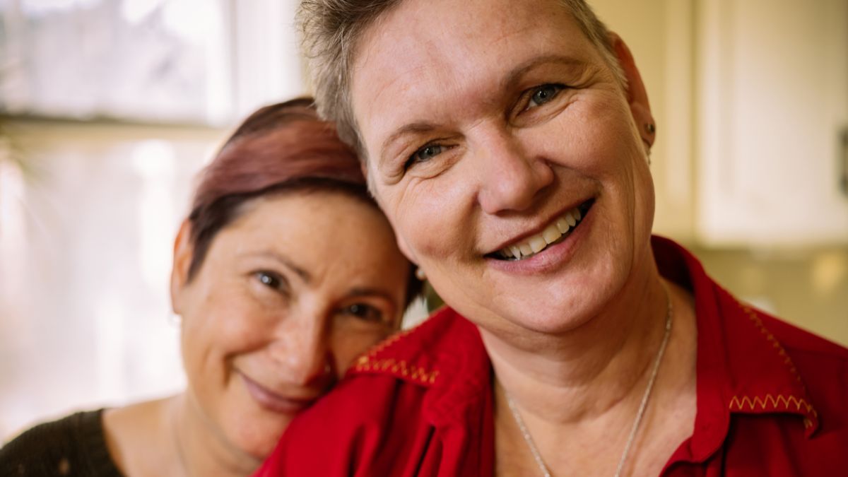Smiling older lesbian couple touch heads