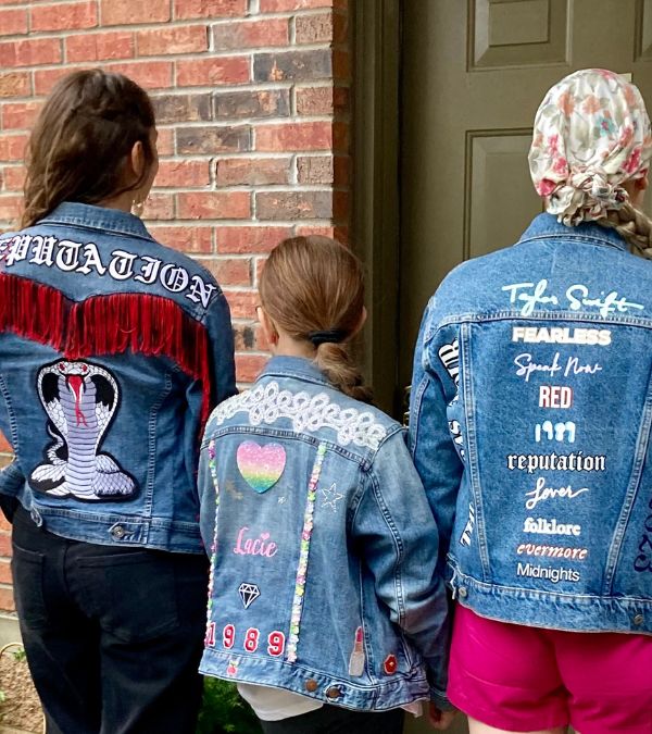 Jenni Hetzel-Gaynor, her sister-in-law, and niece stand with their backs displaying Taylor Swift inspired denim jackets