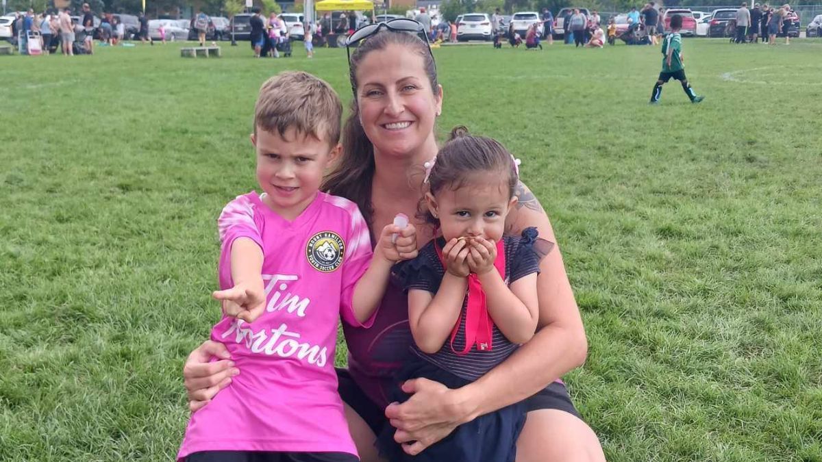 Amy Almas, a young mom, poses with her energetic children, a boy and a girl, on a soccer field