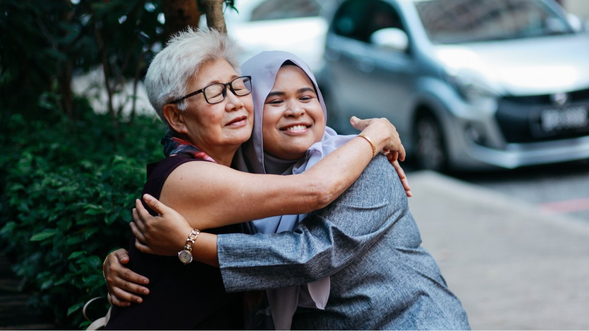 A young and old woman embracing each other.