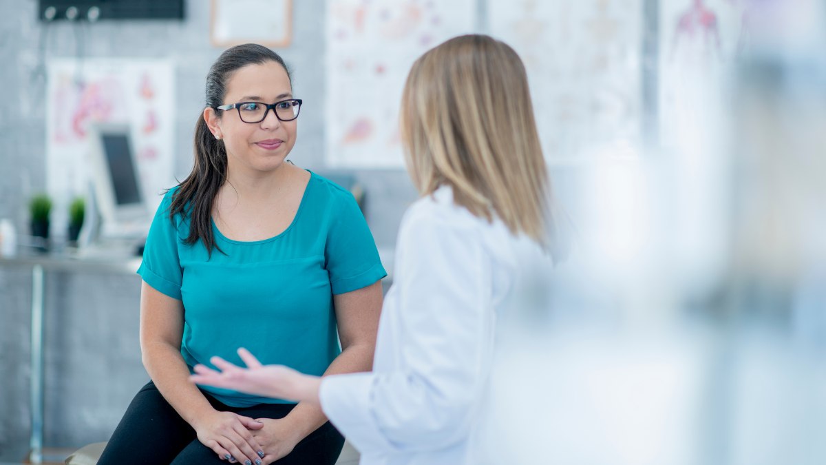 Woman in doctor's office talk to a doctor.