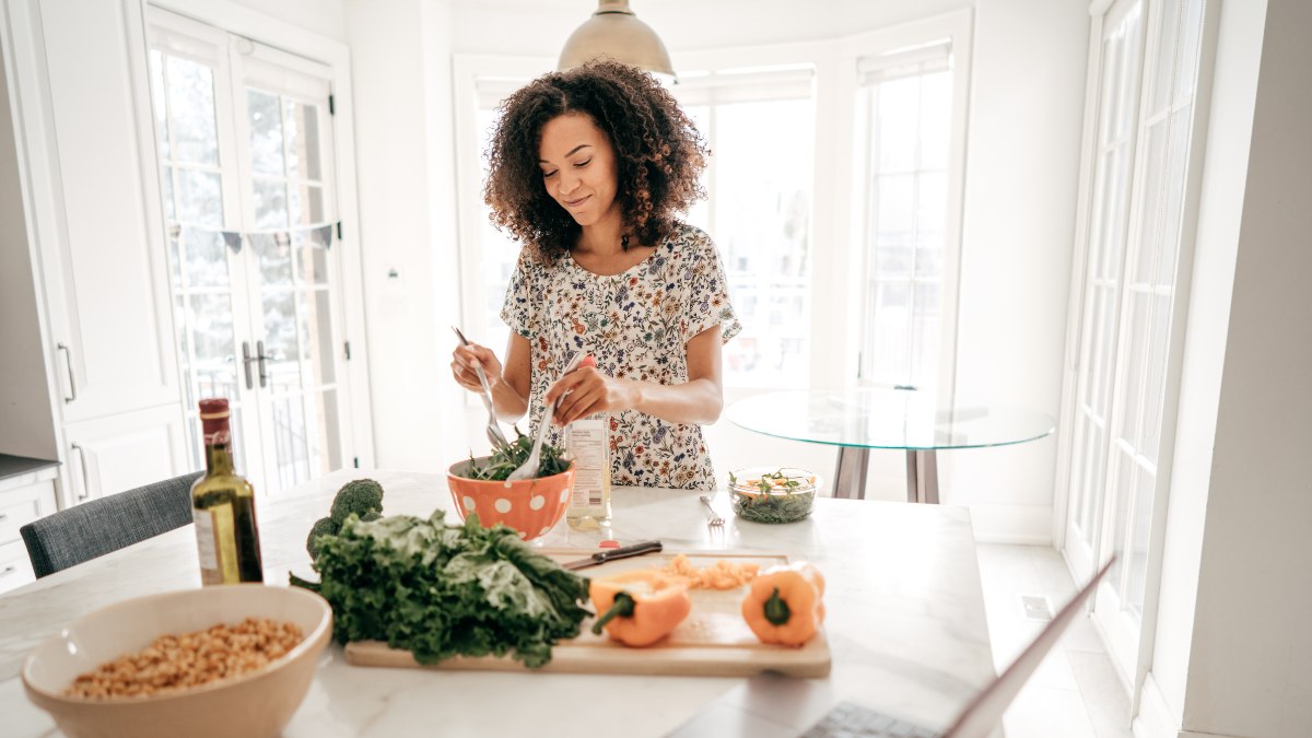 Woman tossing a salad in her kitchen.