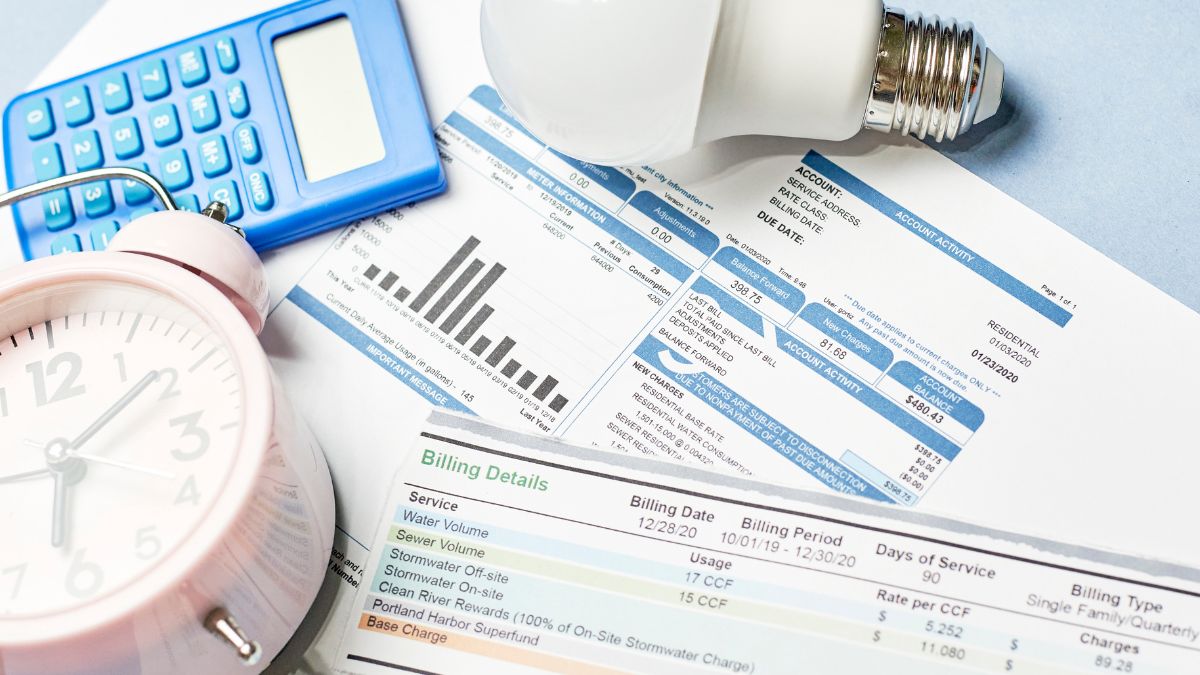 A pile of bills and an alarm clock suggest mounting financial pressure