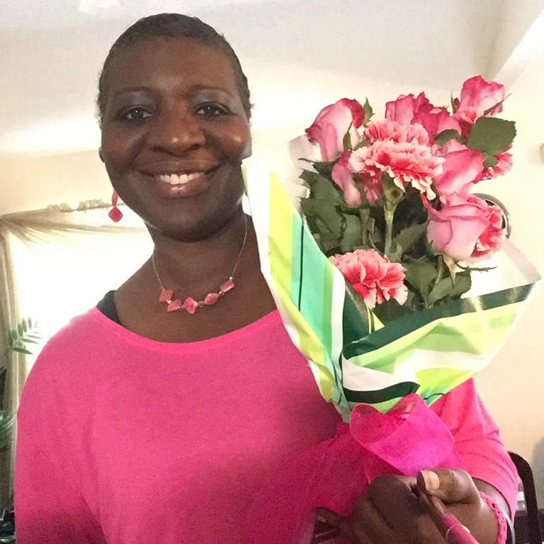 Yvonne Williams smiling with a bouquet of pink flowers.