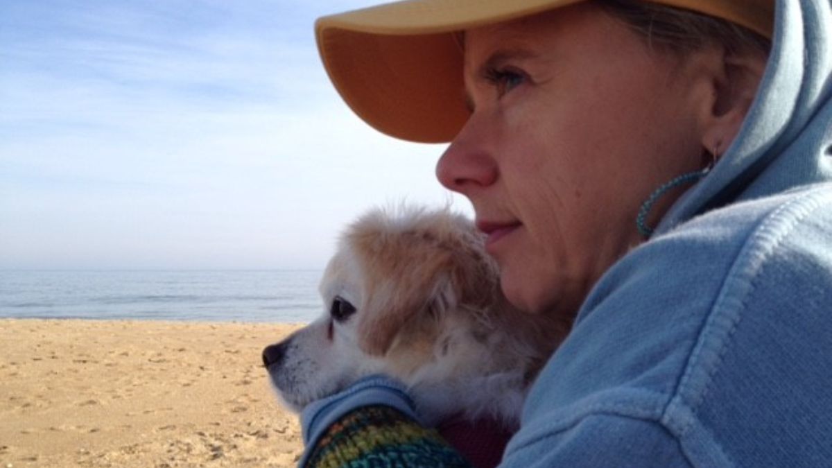 Laura-Lynn Renner hugs her dog PJ as they sit on the beach gazing out at the horizon