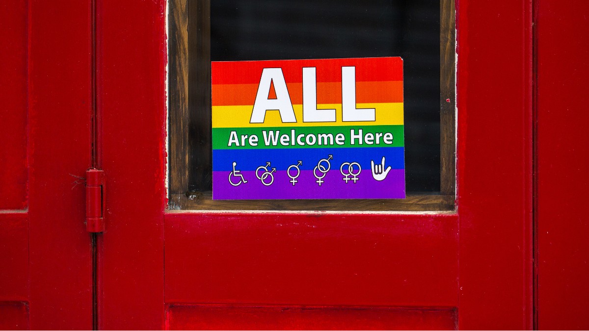 Door with a rainbow sign on it that says "All are welcome here."