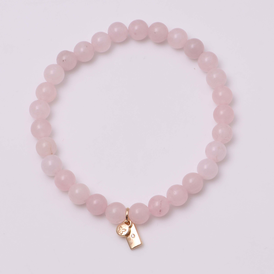 A pink bead bracelet with a small gold charm