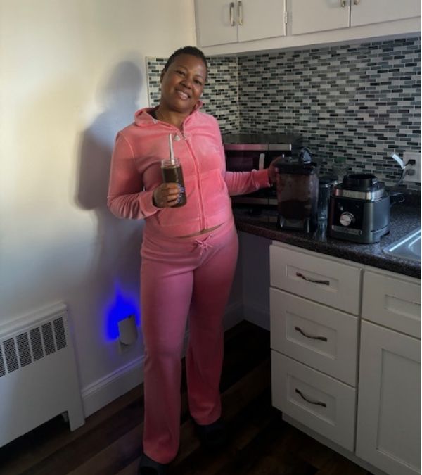 Kelly Choy-Wilson looks pretty in her pink velour loungewear as she stands in her kitchen.